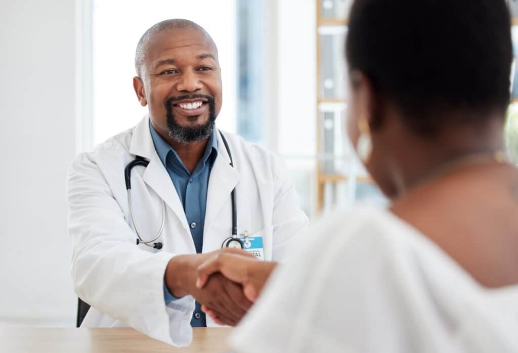 Doctor and patient handshake in the hospital. African american doctor greeting a patient for a chec