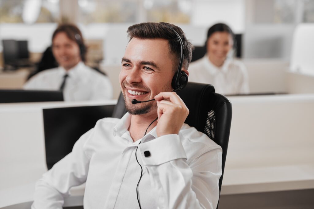 Happy man doing telemarketing in office