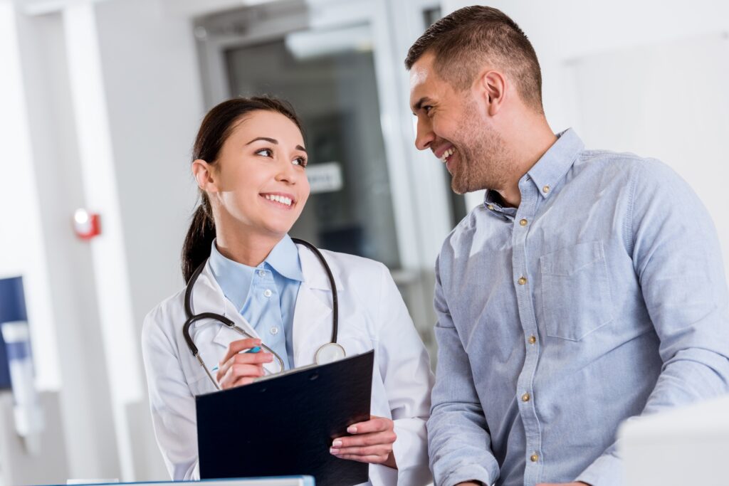 Smiling doctor talking to patient and writing in clipboard