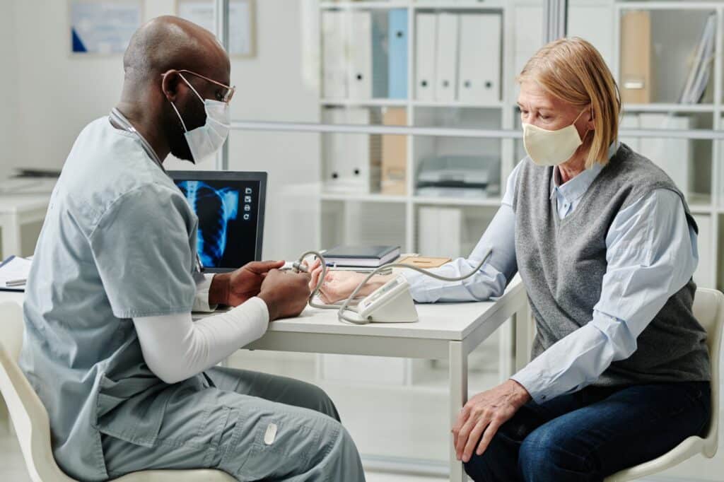 Young African American doctor in uniform measuring blood pressure of patient